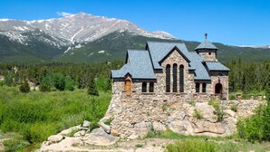 A stone church with a wooden door and arched windows, surrounded by greenery and a mountain in the background. - Estes Park Retreat w/ Views, Heated Pool, Minutes to Town (Estes Park)