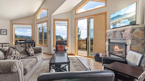 A spacious living room with a fireplace, large windows, and a view of the outdoors. - Estes Park Retreat w/ Views, Heated Pool, Minutes to Town (Estes Park)