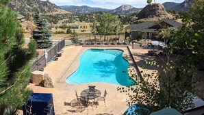 A swimming pool with a patio area, surrounded by mountains and trees. - Estes Park Retreat w/ Views, Heated Pool, Minutes to Town (Estes Park)