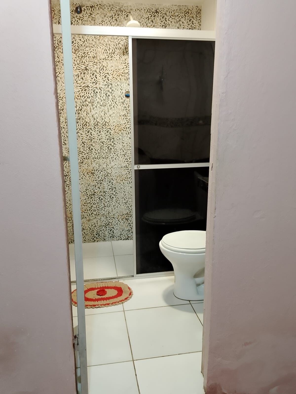 Een badkamer met een wit toilet, een douchegedeelte en een betegelde vloer.