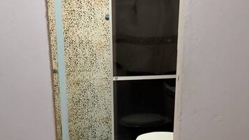 Een badkamer met een wit toilet, een douchegedeelte en een betegelde vloer.