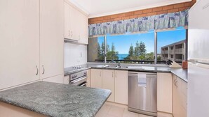 A kitchen with a view of the ocean, a window with a view, and a countertop.