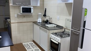A kitchen with white cabinets, a microwave, a blender, a gas stove, and a refrigerator. - Refúgio das Dunas, perfect for those who collect moments with family/friends. (Capim Macio Natal)