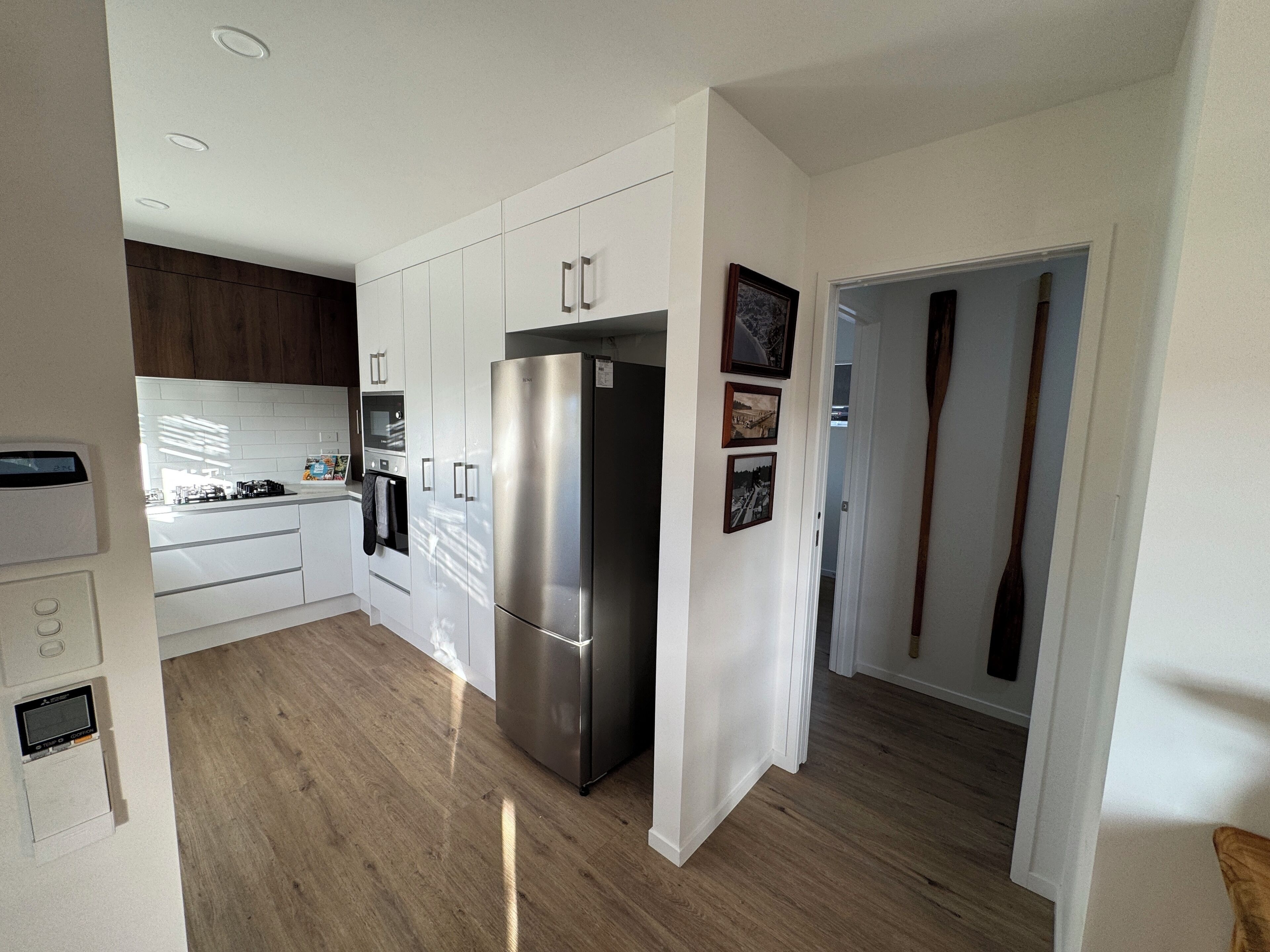 A modern kitchen with white cabinets, a stainless steel refrigerator, and a built-in oven.