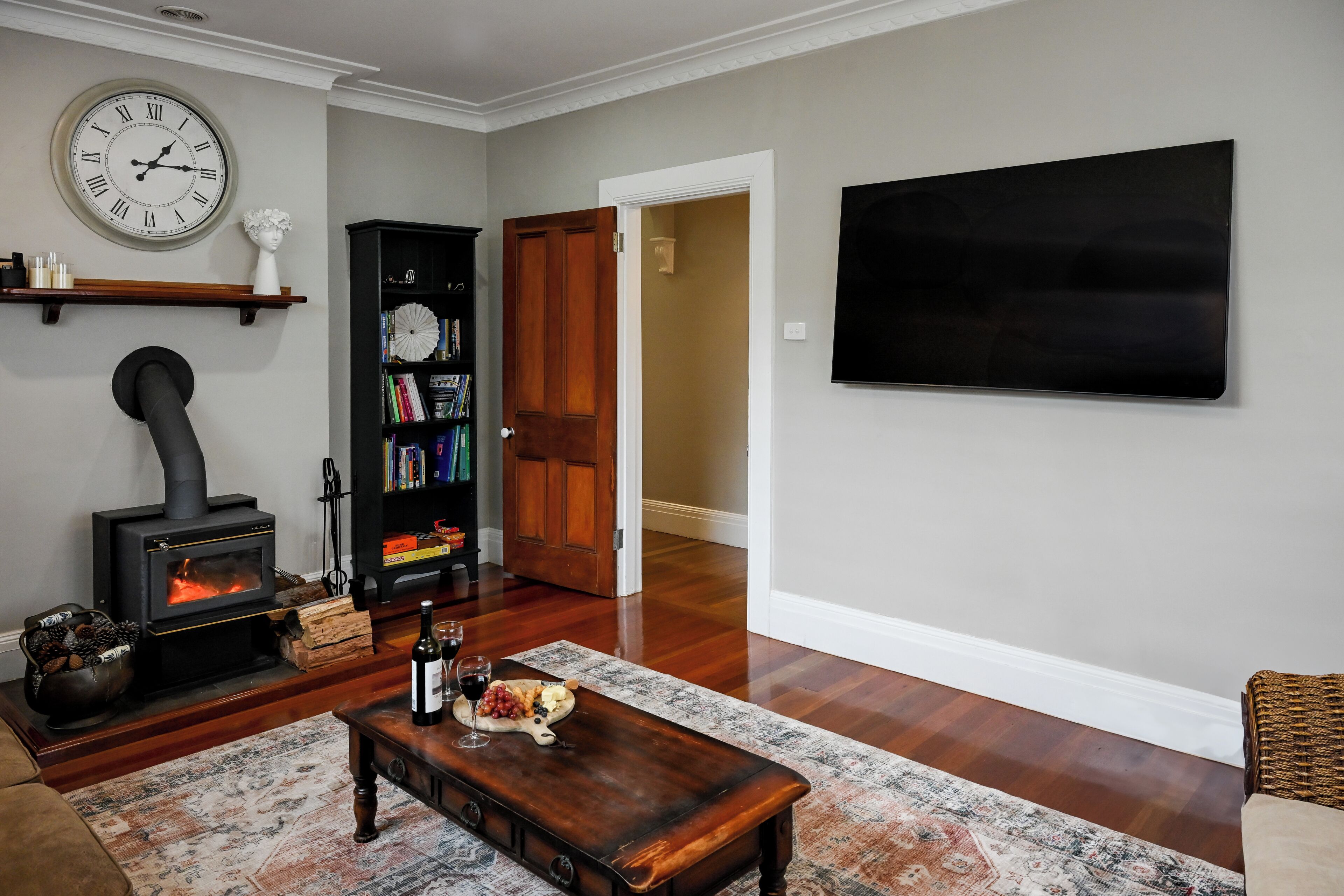 A living room with a fireplace, a clock, a bookshelf, and a flat-screen TV.
