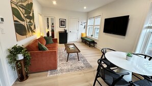 A modern living room with a sofa, coffee table, and dining area.