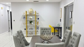 Un coin repas avec une table en bois foncé et quatre chaises à revêtement gris. Un bol décoratif est posé sur la table.