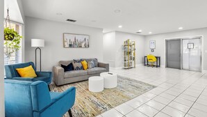 Un salon moderne avec un canapé gris, un fauteuil bleu et un tapis à motifs.