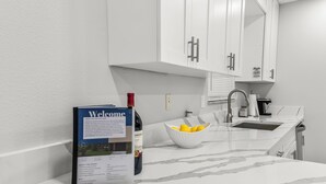 Une cuisine avec des meubles blancs, un évier et un panneau d’accueil.