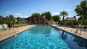 A rectangular swimming pool with clear water, surrounded by lounge chairs and a wooden building in the background. - Open Two-level/3 bdrm/Sleeps 16/Pools & Hot Tubs/Mini-Golf/Family friendly! (St. George)