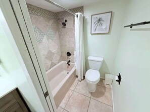 Ein Badezimmer mit Badewanne, Toilette und Duschvorhang.