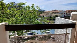 A balcony with a view of a marina and buildings. - Studio with Cabin for 4 – Marina View, Beach Just Steps Away, with Elevator Access (CANET PLAGE)
