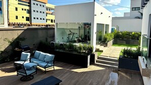 A modern outdoor patio with a seating area, a glass wall, and a view of the cityscape. - Luxury studio pool/gym in east legon at Belrose (Accra)
