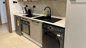 A modern kitchen with a dishwasher, microwave, sink, and built-in oven. - Luxury studio pool/gym in east legon at Belrose (Accra)