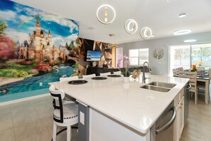 A modern kitchen with a large island, a mural of a castle, and a dining area with a view of the outdoors.