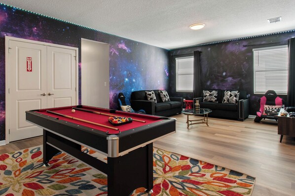 A room with a pool table, a sofa, and a couch.