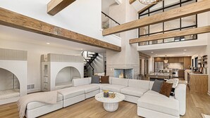 A spacious living area with a large sectional sofa, a round coffee table, and a fireplace. - 🌅 NEW! Waterfront Retreat on West Bay – Hot Tub, Games & Zen Den ➠ 7345 (Traverse City)