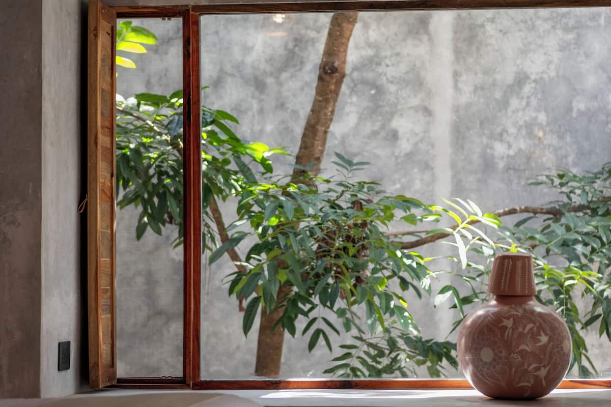 A room with a large window, a wooden bench, and a decorative vase.