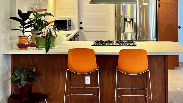 A modern kitchen with a central island, bar stools, a microwave, a stove, and a refrigerator. - Tempe Pool House - Walk to ASU, Midcentury Wonder! (Tempe)