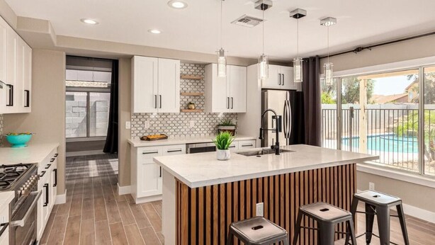 A modern kitchen with white cabinets, a central island, and pendant lighting.