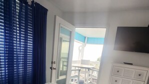 Ein Schlafzimmer mit Bett, Deckenventilator, Fernseher und Blick ins Freie.