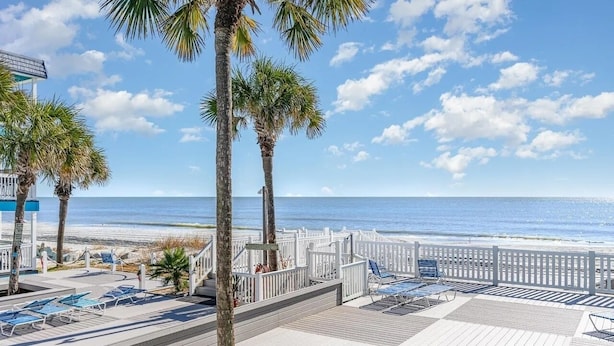 A beachside resort with a wooden deck, lounge chairs, and palm trees. - Beach House at Garden City. 2-BR condo with private pool, on the beach. (Murrells Inlet)