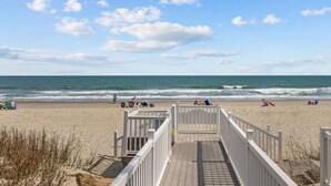 A wooden boardwalk leading to a sandy beach with a view of the ocean and a clear sky. - Beach House at Garden City. 2-BR condo with private pool, on the beach. (Murrells Inlet)