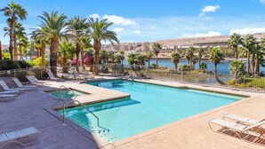 A swimming pool with lounge chairs, palm trees, and a view of a body of water and distant hills. -  3 BDR Riverfront Resort w/pool, spa, dock & launch! (Bullhead City)