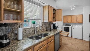 A kitchen with granite countertops, wooden cabinets, a built-in oven, a dishwasher, and a window with blinds. - Centrally located home in the heart of Tucson (Tucson)