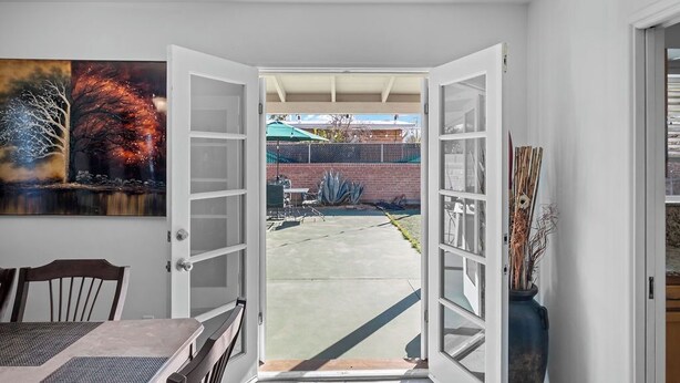 An open door leading to a backyard with a patio, a brick wall, and a green umbrella. - Centrally located home in the heart of Tucson (Tucson)