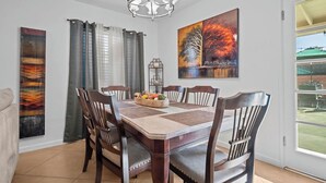 A dining room with a wooden table, six chairs, a chandelier, and artwork on the walls. - Centrally located home in the heart of Tucson (Tucson)