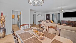 A dining area with a chandelier, a table set with a centerpiece, and a living room with a sofa and a flat-screen TV. - Centrally located home in the heart of Tucson (Tucson)