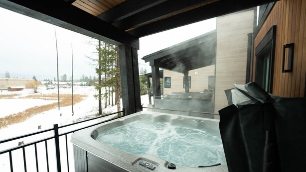 Un bain à remous doté d’un panneau de commande, d’un plafond en bois et offrant une vue sur un paysage enneigé.