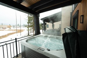 Un bain à remous doté d’un panneau de commande, d’un plafond en bois et offrant une vue sur un paysage enneigé.