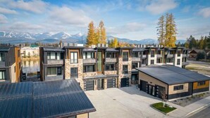 Un immeuble résidentiel moderne à plusieurs étages, doté d’une façade en pierre, de grandes fenêtres et d’un toit plat.