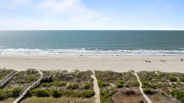 A beach with a wooden boardwalk leading to a dune area.