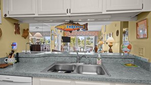A kitchen with white cabinets, a granite countertop, and a fish hanging from the ceiling.