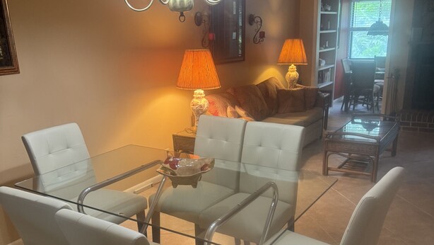 A dining area with a glass table and white chairs, a sofa, and a lamp. - Pet friendly Spacious townhome, quiet neighborhood with pool, 1/2 mile to beach (St. Simons Island)