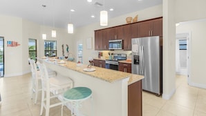 A modern kitchen with a central island, stainless steel appliances, and pendant lighting. - Canal Views & Private Pool - Nirvana on Niagara - Roelens Vacations (Cape Coral)