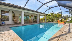 A covered swimming pool with a patio area, outdoor furniture, and a view of the surrounding landscape. - Canal Views & Private Pool - Nirvana on Niagara - Roelens Vacations (Cape Coral)