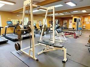 A gym with treadmills, weight machines, and a mirror.