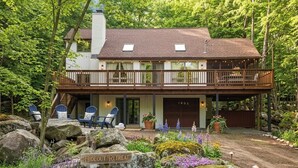 Ein zweistöckiges Haus mit Balkon, einem Schild mit der Aufschrift 'Hideout Retreat' und Außenmöbeln.
