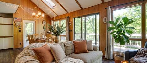A cozy living room with a large sofa, a dining area, and a view of the outdoors.