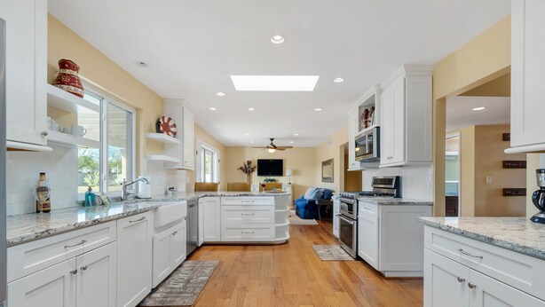 A modern kitchen with white cabinetry, a central island, and a ceiling fan.