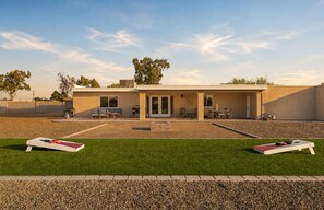 Un edificio moderno con un patio, mobiliario exterior y un césped bien cuidado.