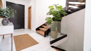 Ein modernes Interieur mit Treppe, einer Holztür, einer weißen Wand und einem Blumentopf.