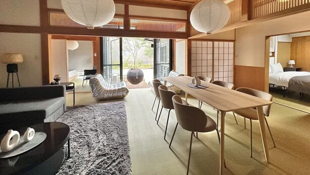 A modern hotel room with a dining area, a sofa, a large window, and a traditional Japanese sliding door. - Spacious Traditional Japanese house by Restavio (Ozu, Kikuchi District)