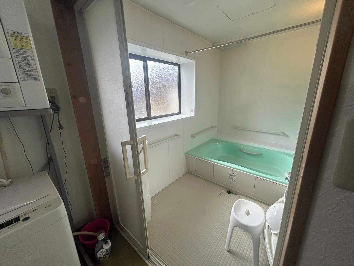 A small, compact bathroom with a bathtub, a window, and a toilet.