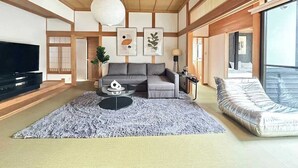 A modern living room with a sofa, a coffee table, and a TV. - Spacious Traditional Japanese house by Restavio (Ozu, Kikuchi District)