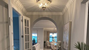 A spacious hallway with a chandelier, a dining area with a table and chairs, and a view of the outdoors. - Fabulous 3-bedroom house with private pool and endless amenities in Estero (Estero)